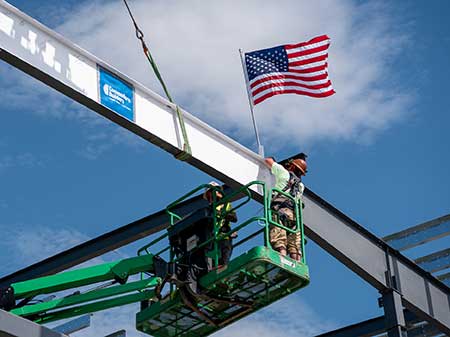 Construction worker secures the last steel on the new DPW building