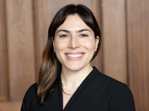 White woman with brown hair smiling wearing black shirt posing for headshot.