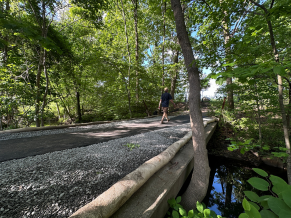 A man walks from Drake Village to the path around Arlington Reservoir on the new accessible path. 