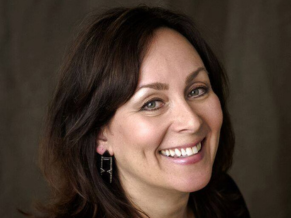 Brunette white woman smiling in headshot with makeup on.