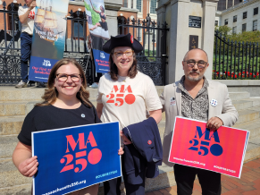 Two women and one man holding a sign that reads, 