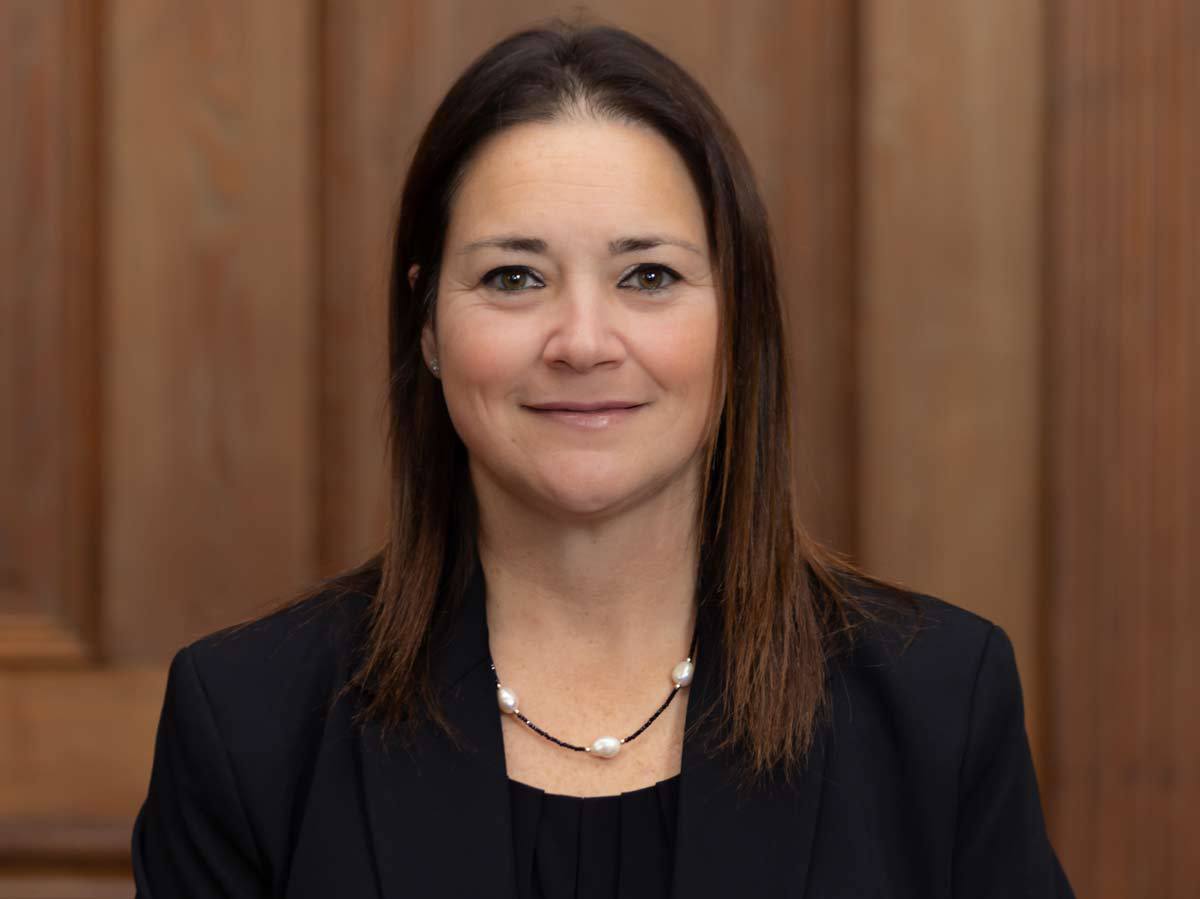 Headshot of brunette white woman smiling dressed in business casual.